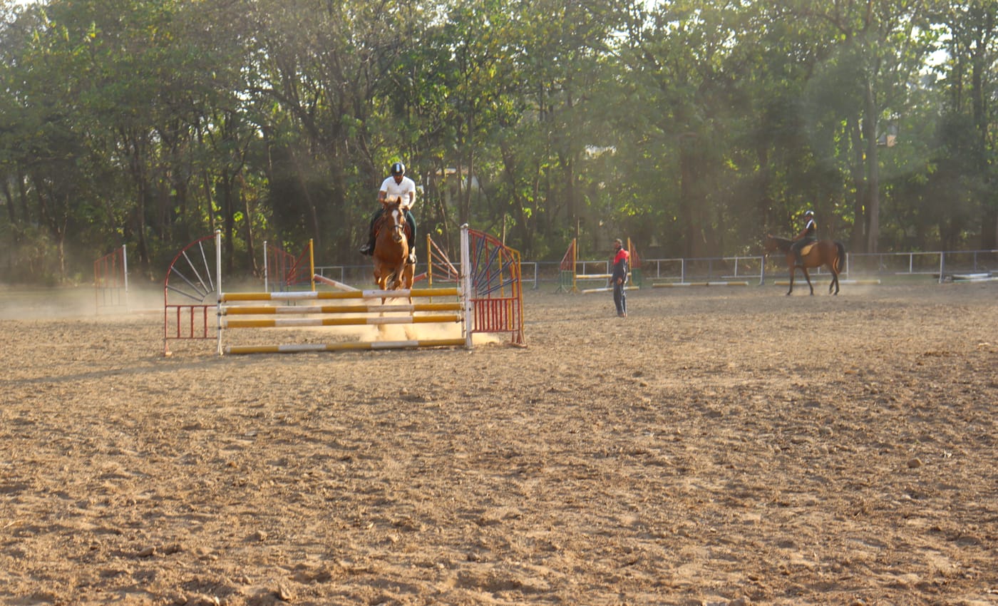 A rider clearing a jump on horseback during riding drill